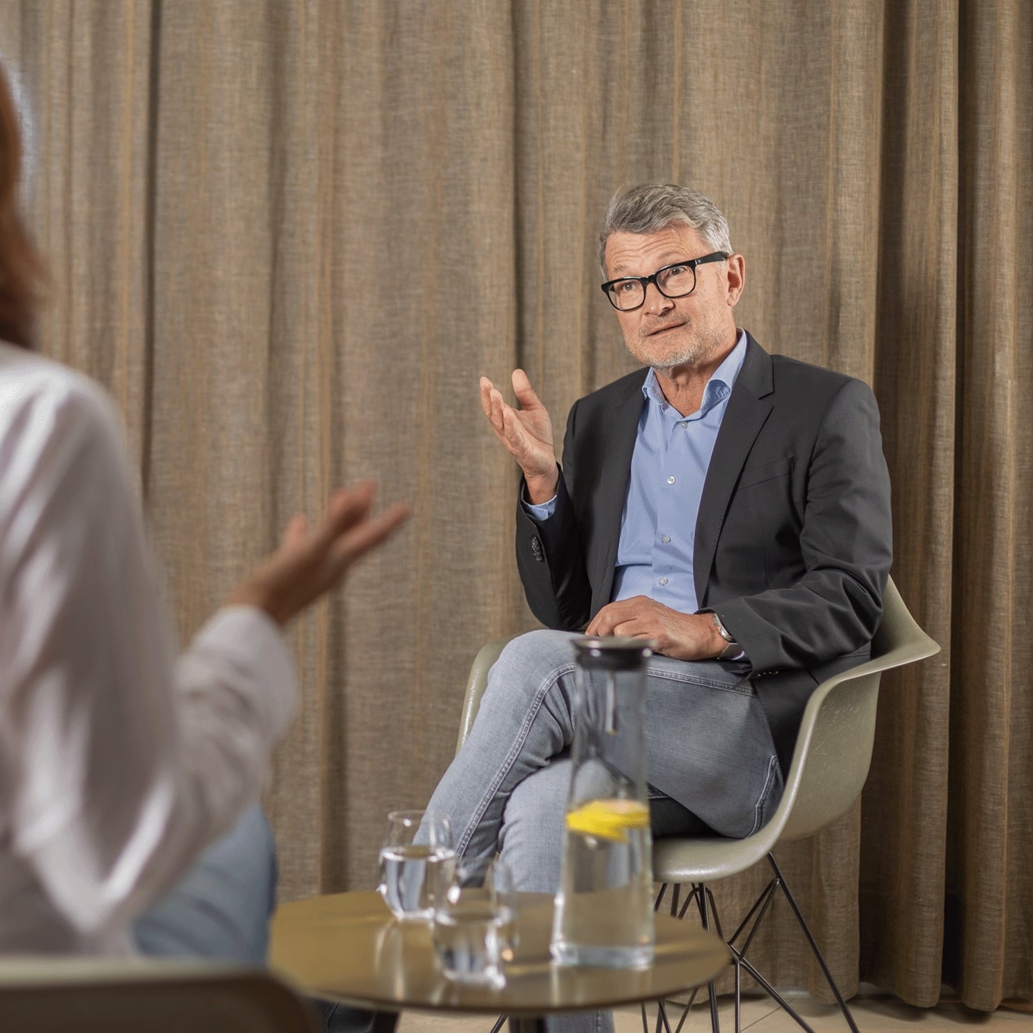 Thomas Wachter sitzt im Gespräch mit einer weiteren Person und gestikuliert während einer Beratung.